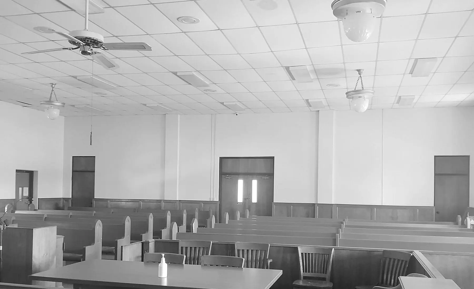 Fotografia de uma sala de tribunal vazia, com bancos e mesas de madeira